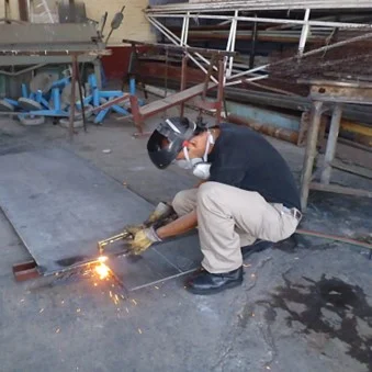 TRABAJADOR REALIZANDO EL CORTE DE UN TROZO DE PLACA, POR MEDIO DE OXICORTE