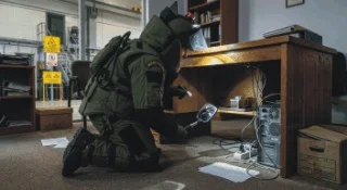 PERSONAL CON EQUIPO ANTIBOMBAS REALIZANDO REVISION Y BUSQUEDA DE POSIBLES EXPLOSIVOS EN LAS INSTALACIONES